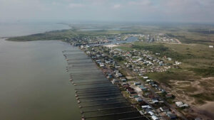 Coastal village with docks and grassy fields.