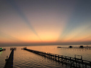 Sunset over calm water with piers.