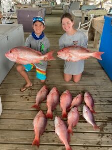 Two people holding large red snappers.