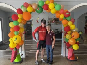 Cyclist and woman beneath festive balloon arch.