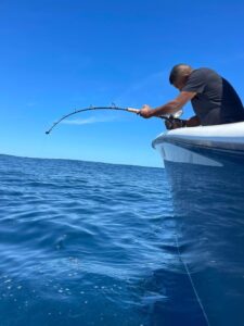 Man fishing from boat in open ocean.